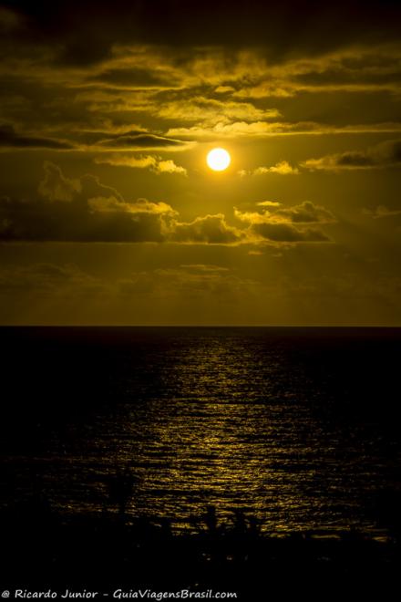 Imagem do sol sob as águas da praia em Trancoso em um maravilhoso anoitecer.
